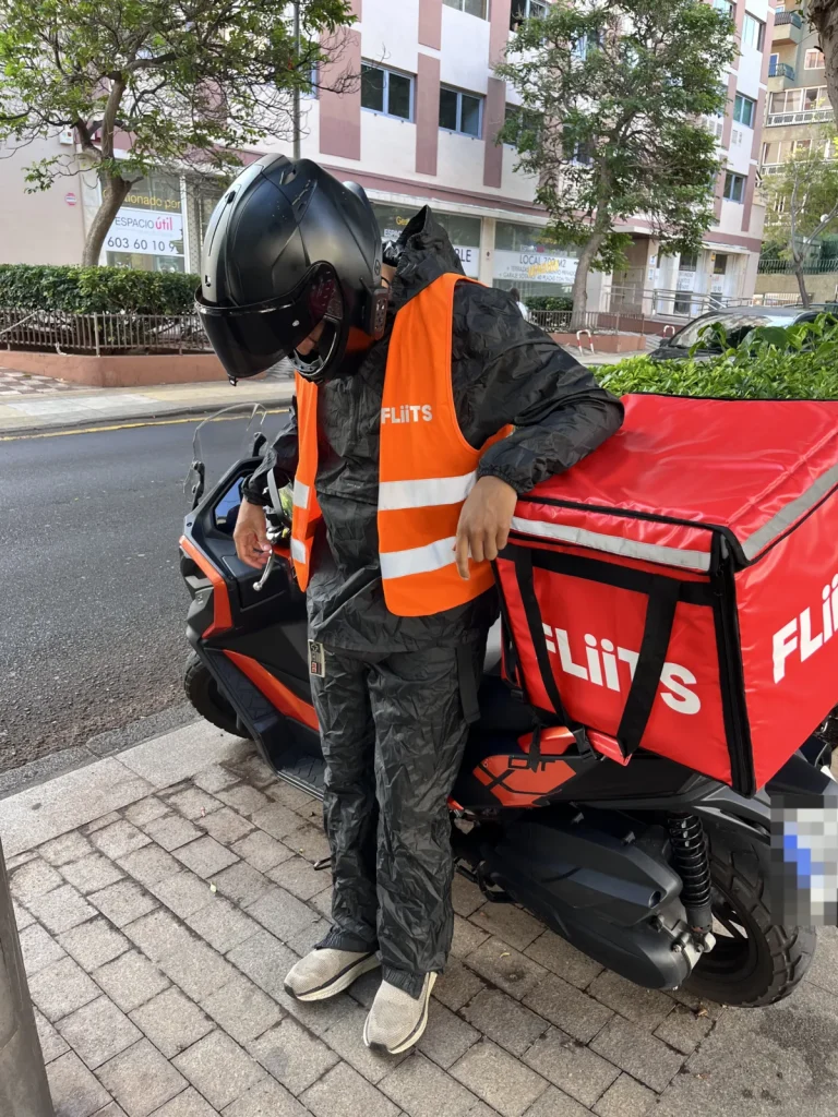 Mateo con el chubasquero y el pantalón de agua de Decathlon puestos, junto a la moto