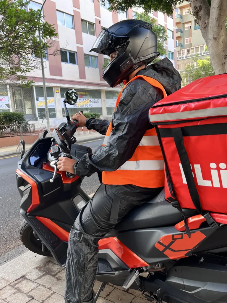 Mateo sentado en la moto con el traje de agua de Decathlon y el chaleco reflectante